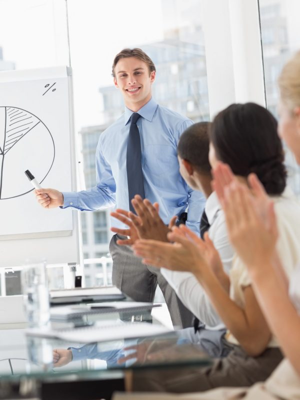 Businessman being applauded for his presentation in the office