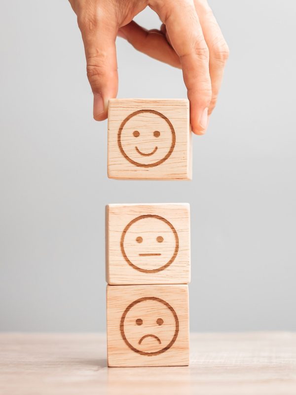 Man hand holding emotion face block. Customer choose Emoticon for user reviews. Service rating, ranking, customer review, satisfaction, evaluation and feedback concept
